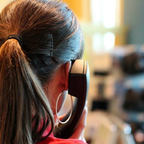 Frau von hinten fotografiert hätlt einen Telefonhörer in der Hand